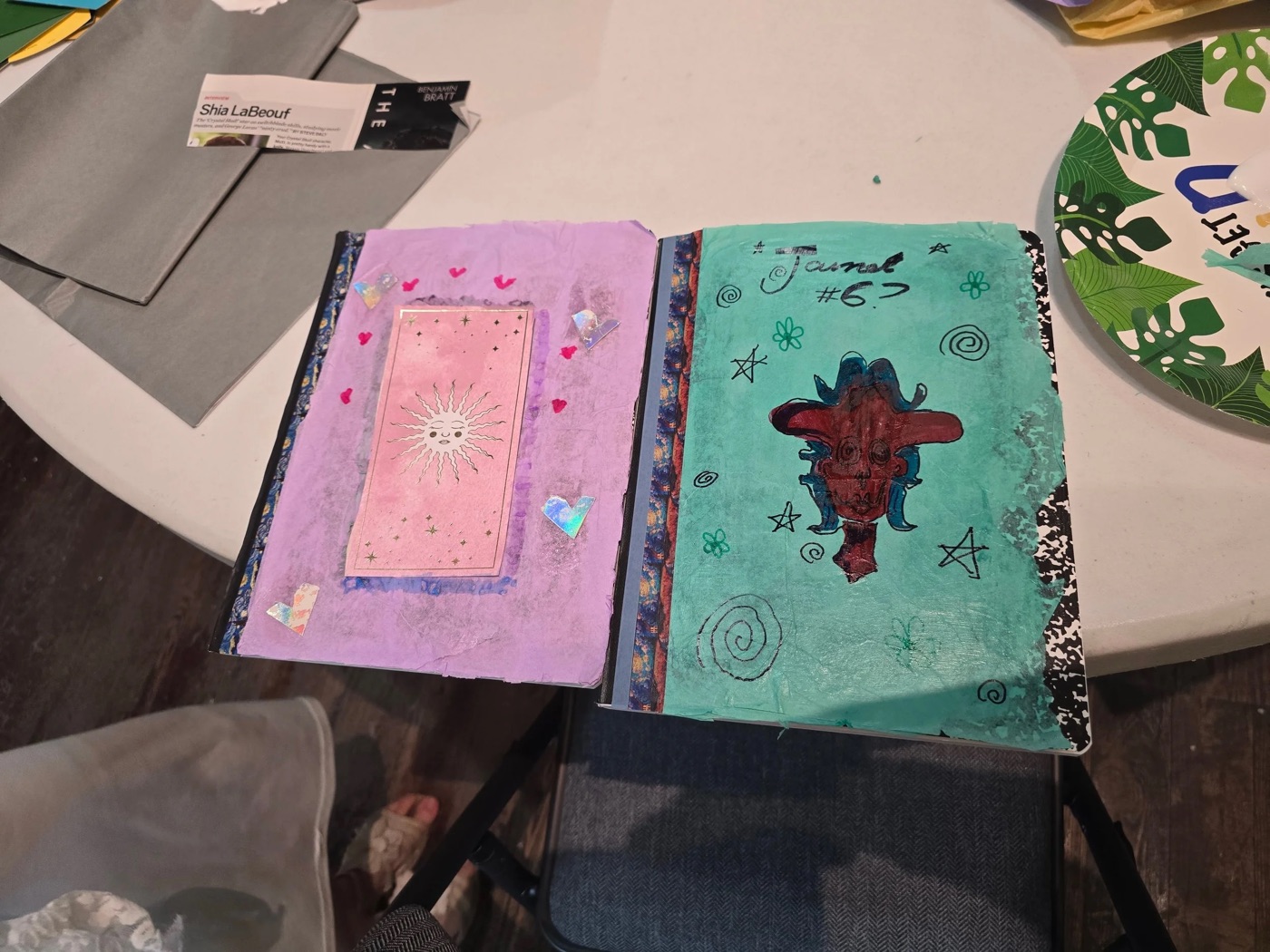 A decoupaged composition notebook cover — floral coloring-book art with strips of pink and grey tissue paper.