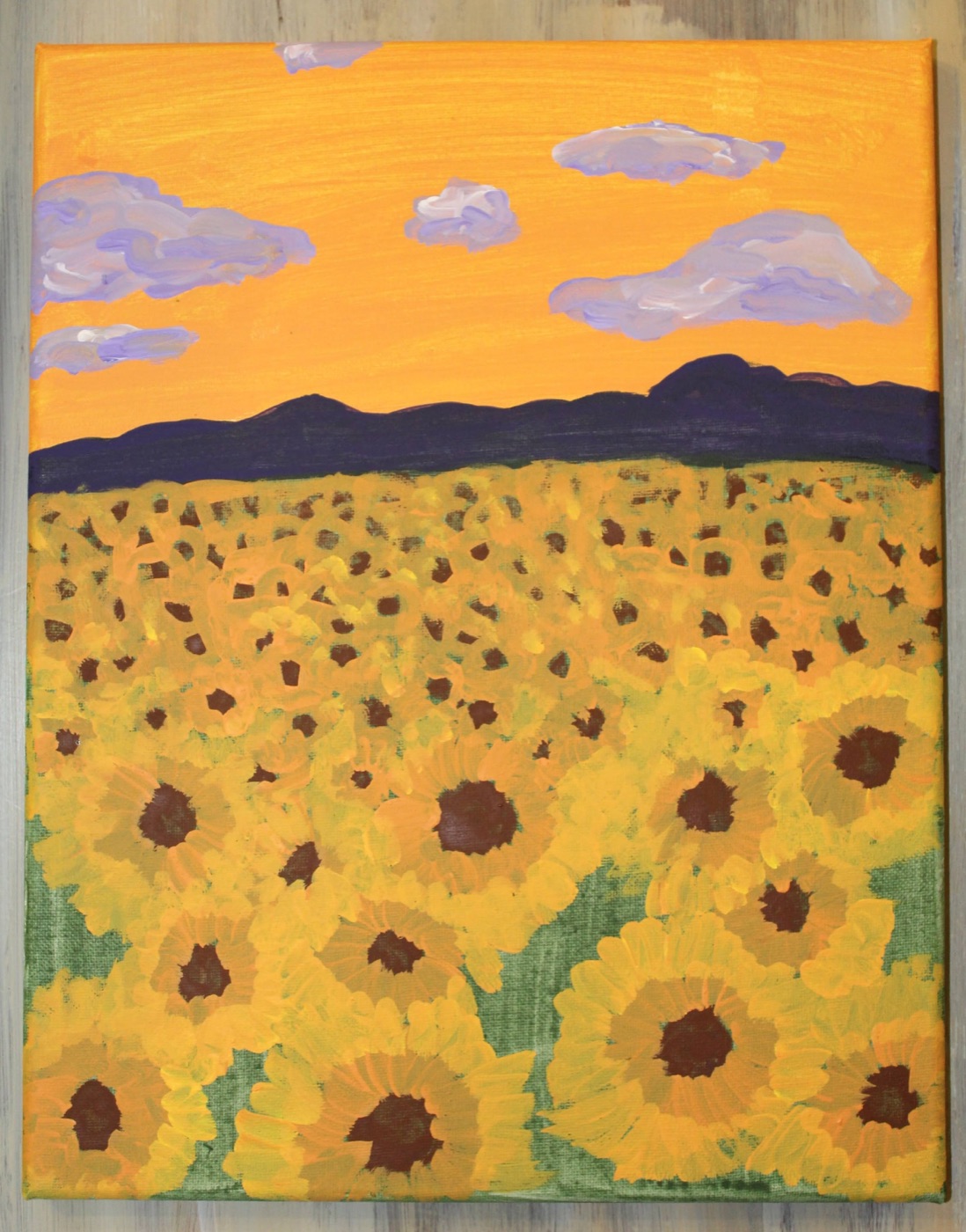 An acrylic painting of a sunflower field at sunset, with a vibrant orange sky, purple clouds, and dark mountains.